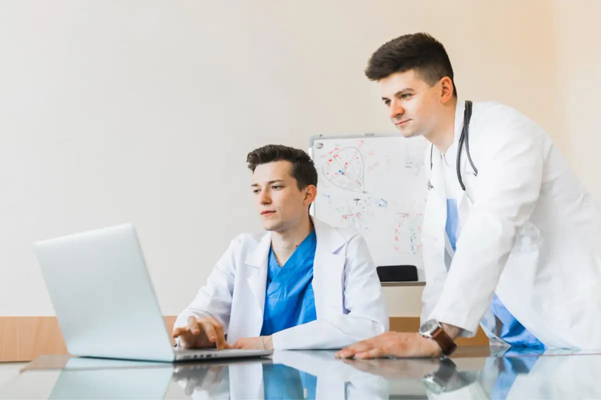 Two doctors working together at a laptop in a small practice